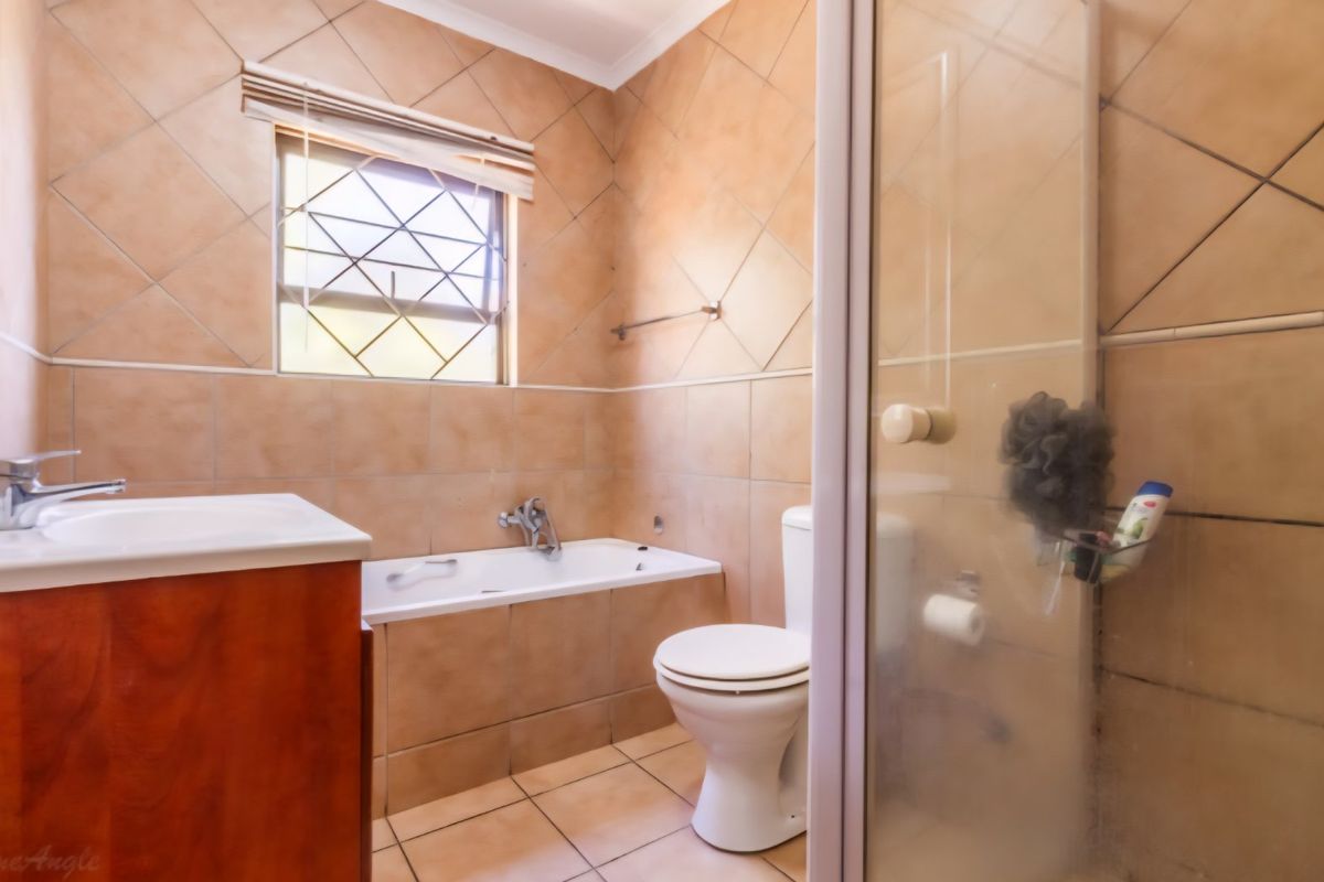 A functional bathroom featuring a built-in bathtub, separate shower enclosure, vanity cabinet, and neutral ceramic tiling throughout.