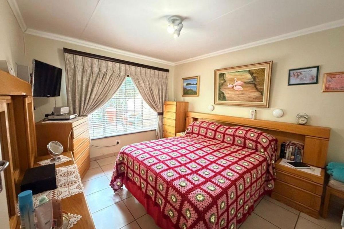 A well-maintained bedroom featuring tiled flooring, a built-in headboard, and a window with curtain tracks, offering a functional and comfortable living space.