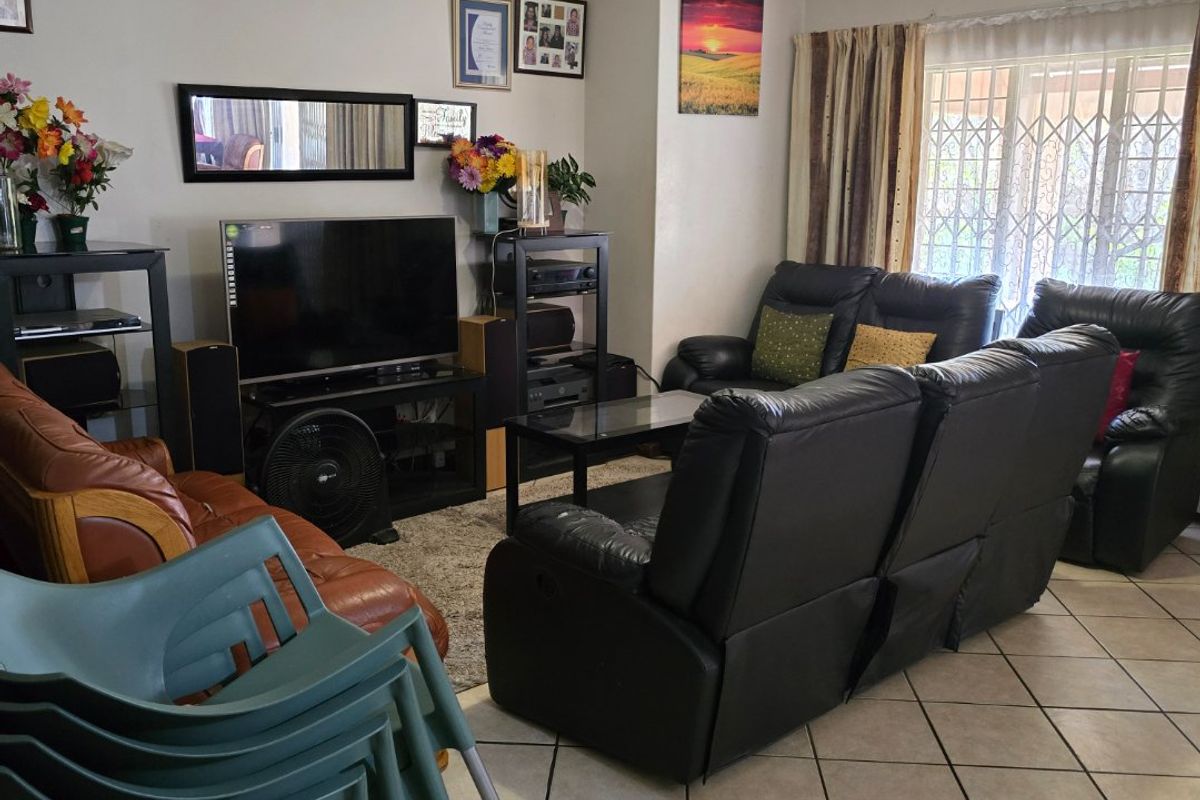 A living room featuring tiled flooring, coving, and a large window with security gate and curtain rails.