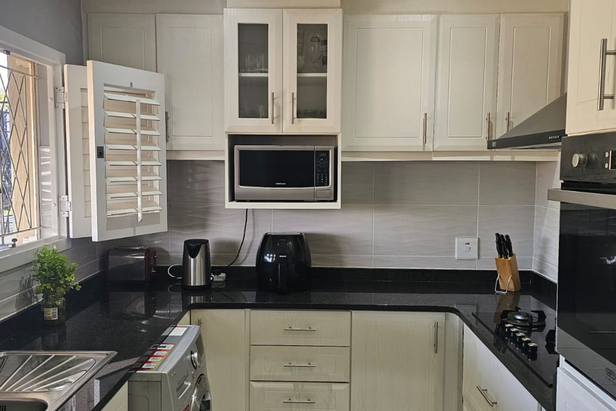A well-maintained kitchen featuring granite countertops, shaker-style cabinetry, built-in oven, gas hob, and an integrated microwave, offering a functional and modern cooking space.