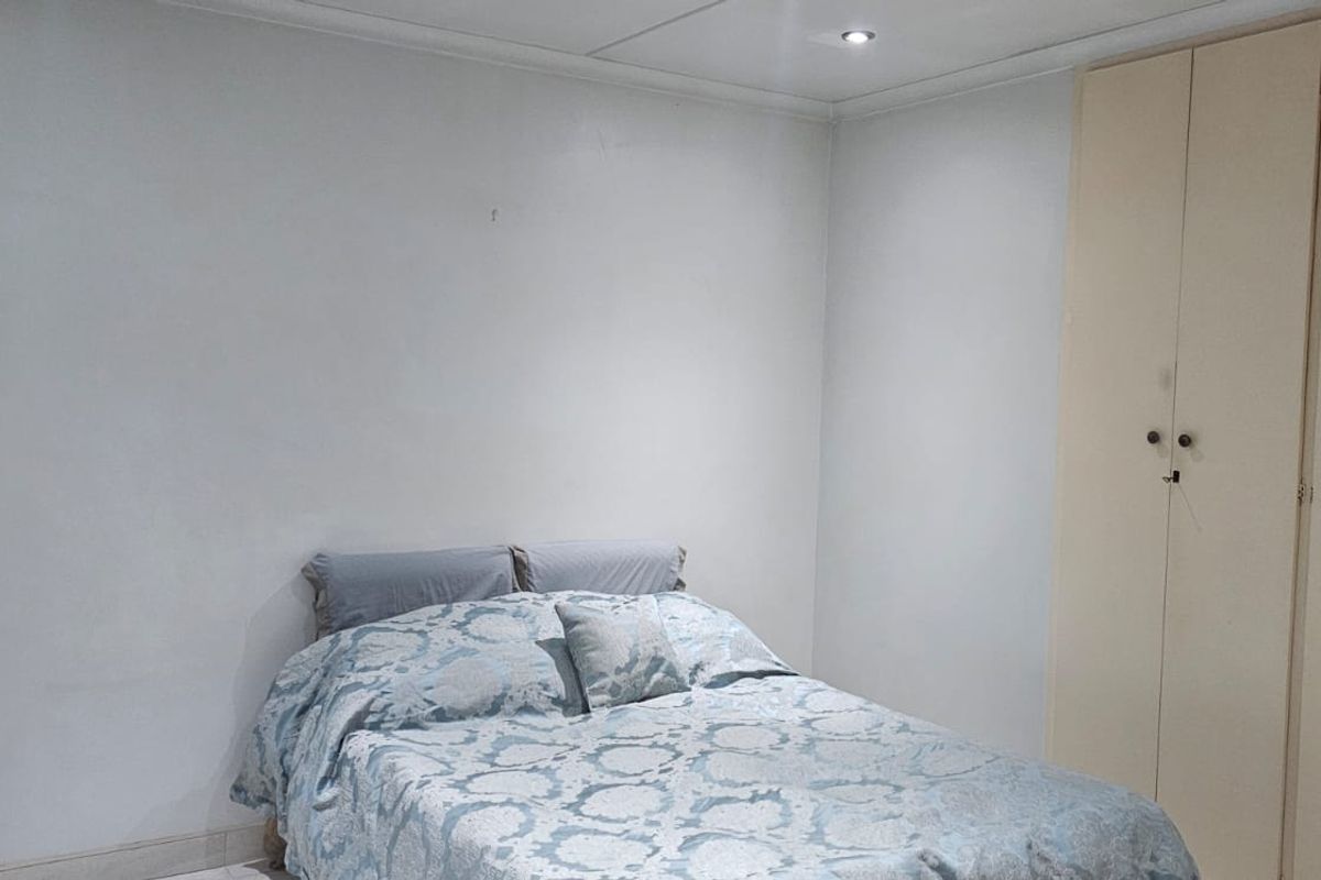 A functional bedroom featuring built-in cupboards and recessed ceiling lighting, providing a neutral base for personalization.