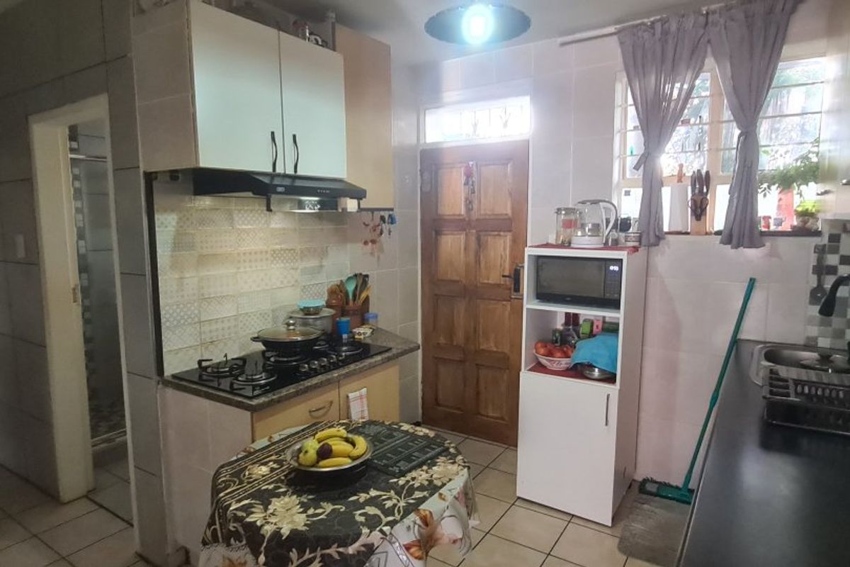 Functional kitchen featuring a gas hob, extractor fan, tiled splashbacks, and built-in cabinetry with direct access to the exterior.