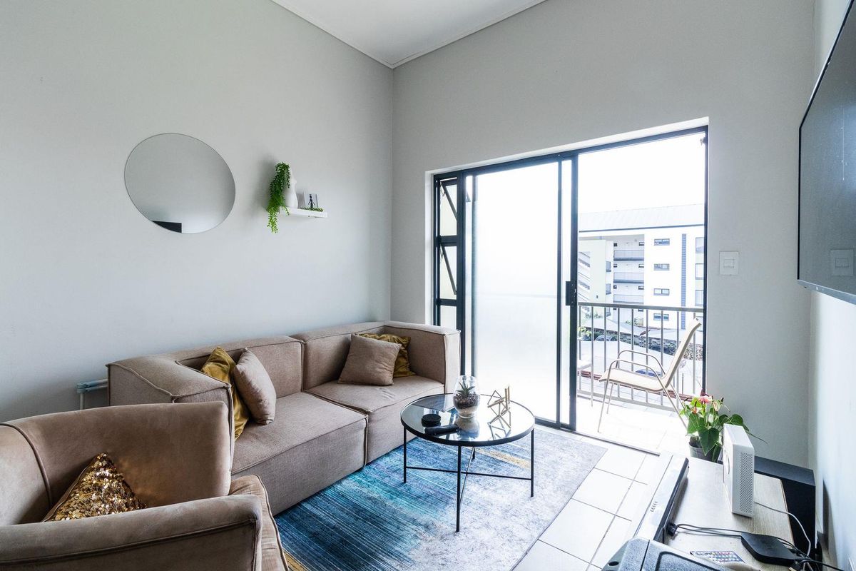 A bright living room featuring tiled flooring and a large sliding glass door that provides access to an outdoor balcony area.