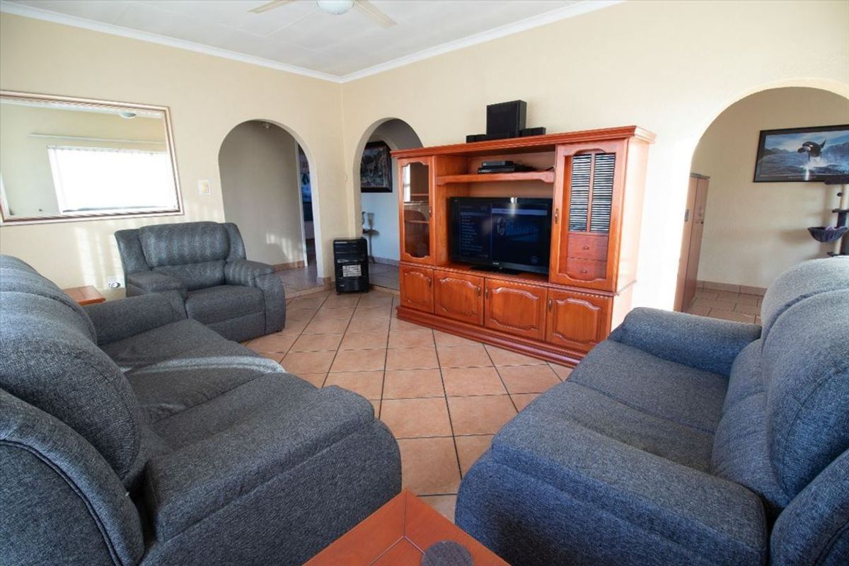 A living room featuring tiled flooring, a ceiling fan, and distinctive archway openings leading to adjacent spaces.