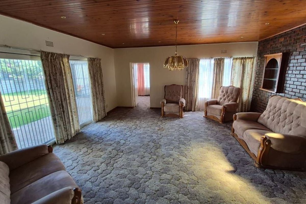 Spacious living room featuring an exposed brick feature wall, timber ceiling, and large sliding doors providing access to the garden.