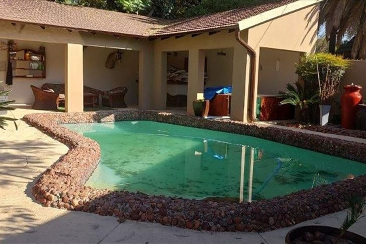 Outdoor pool area featuring a swimming pool with stone coping and an adjacent covered patio space.