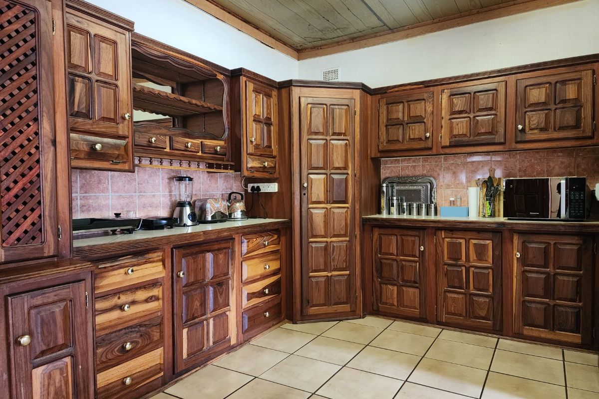 A traditional kitchen featuring extensive dark wood cabinetry, tiled backsplash, and durable floor tiles, offering a classic aesthetic with potential for modern updates.