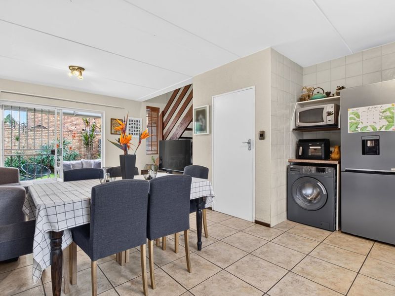 Open-plan living and dining area featuring tiled flooring, a staircase, and direct access to a rear patio through sliding glass doors.