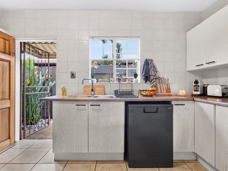 Functional kitchen featuring laminate cabinetry, tiled backsplash, and direct access to an outdoor area, providing a practical layout for daily meal preparation.