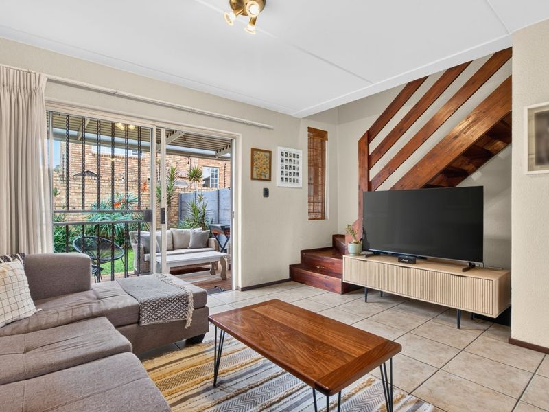 Open-plan living area featuring tiled floors, a wooden staircase, and large sliding glass doors providing direct access to the rear patio and garden.