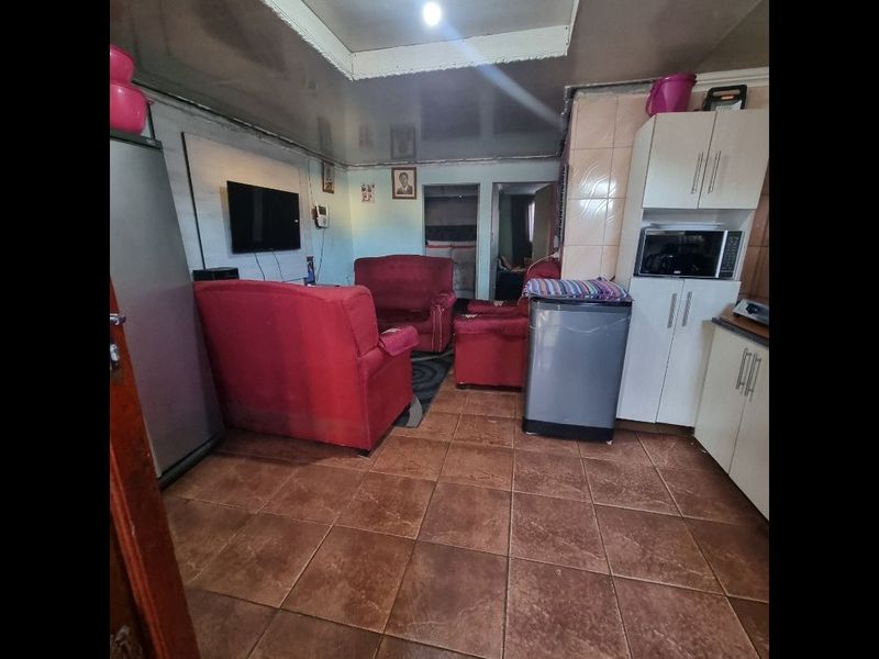 Open plan living and kitchen area featuring tiled flooring and built-in cabinetry, offering a functional layout with potential for cosmetic updates.