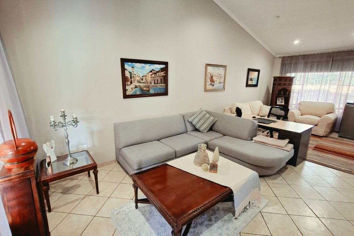 Spacious living room featuring vaulted ceilings, tiled flooring, and recessed lighting, offering a comfortable and well-lit area for relaxation.