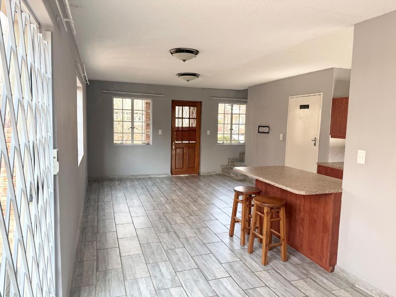 Open plan living area featuring tiled flooring, a breakfast bar, and direct access to the exterior via a security gate.