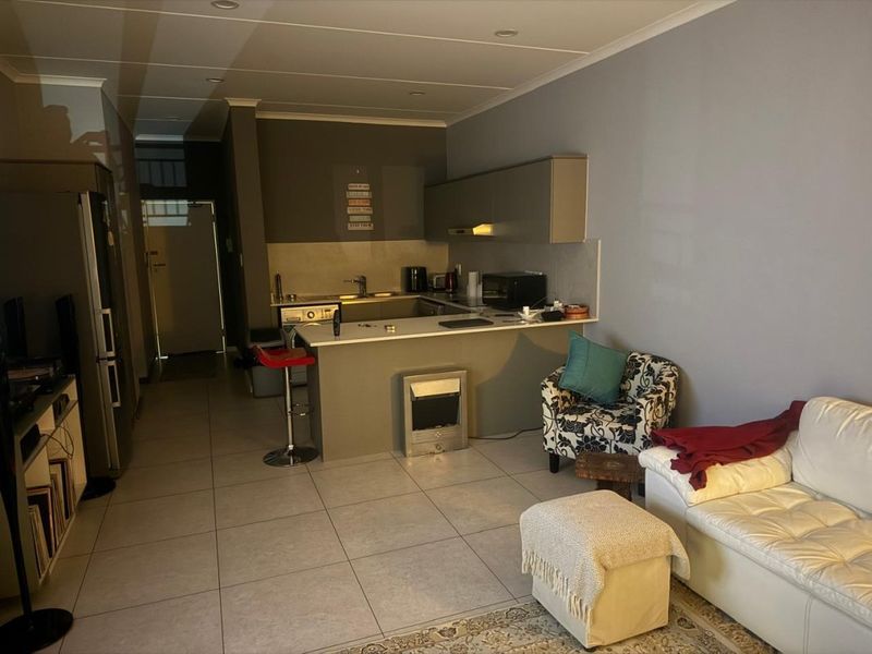 Open-plan living area featuring a compact kitchen with breakfast bar, tiled flooring, and neutral wall finishes.