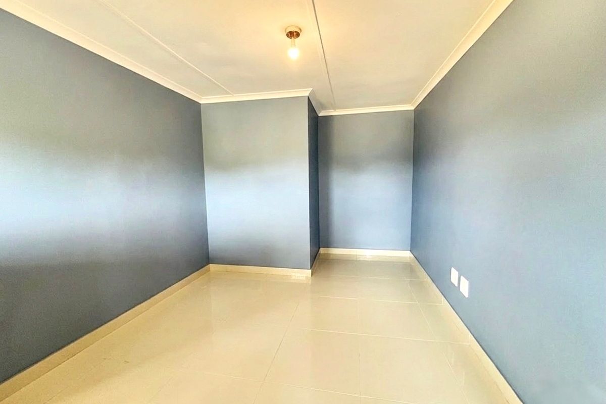 A clean, empty bedroom featuring neutral tiled flooring and blue-painted walls, providing a versatile blank canvas for personalization.