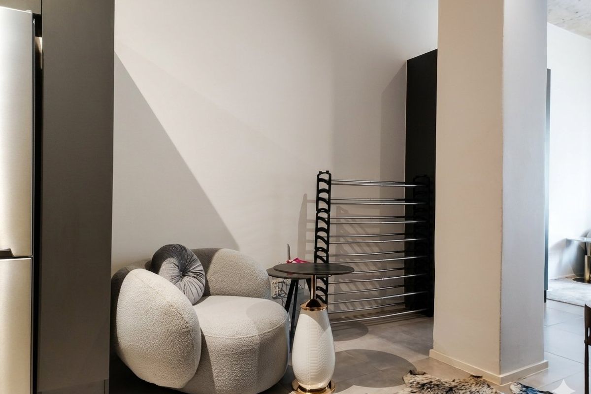 A modern living area featuring neutral walls, tiled flooring, and integrated dark cabinetry, offering a clean and contemporary aesthetic.