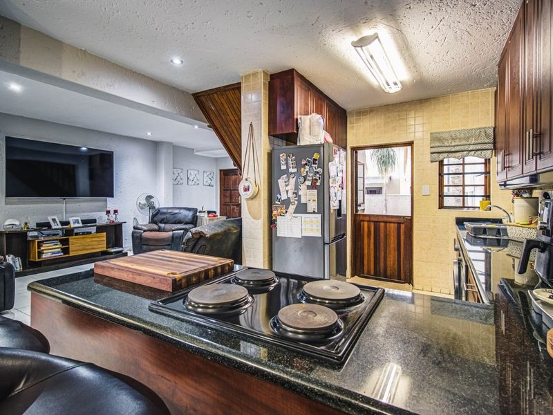 Open-plan kitchen and living area featuring dark wood cabinetry, granite countertops, an electric hob, and a classic stable door leading to the exterior.