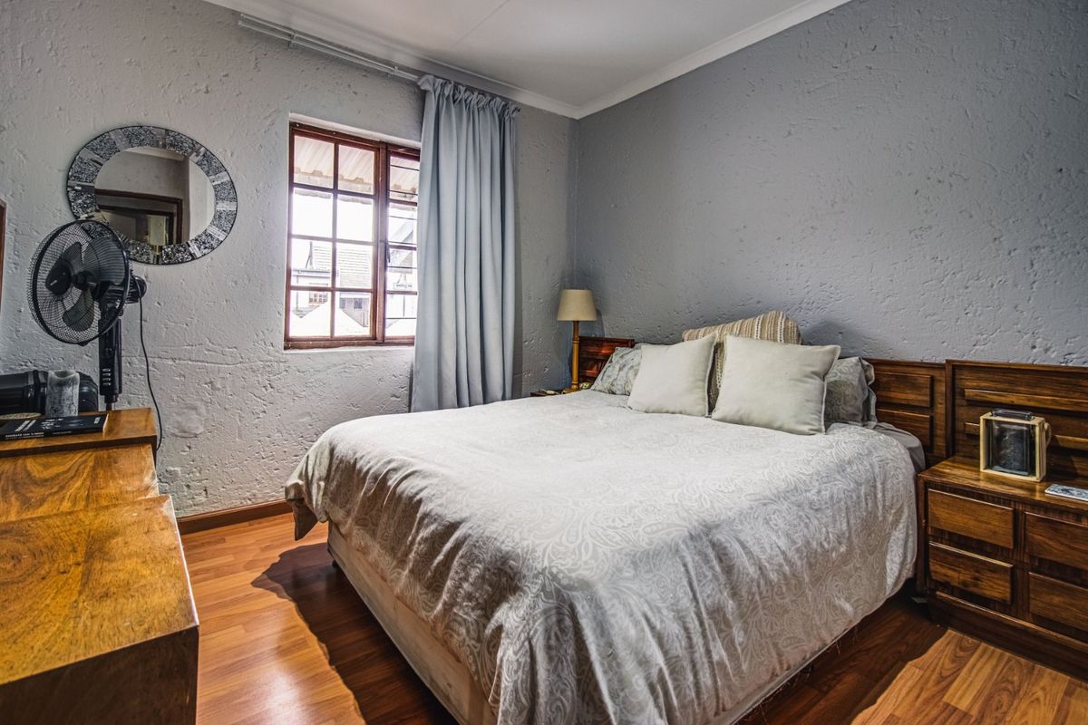 A cozy bedroom featuring textured walls, laminate flooring, and a timber-framed window, offering a comfortable and functional living space.