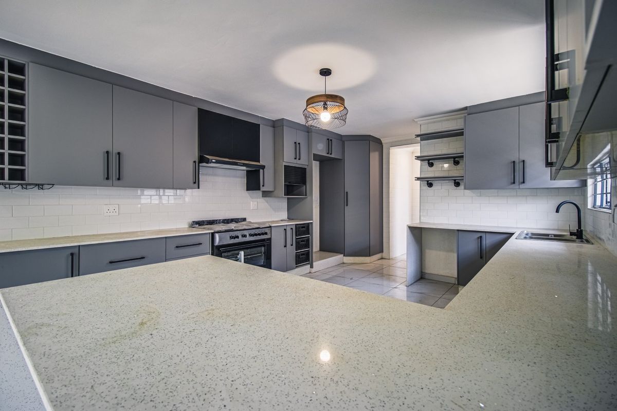 Modern kitchen featuring grey cabinetry, stone countertops, subway tile backsplash, and integrated appliances, offering a clean and functional culinary space.