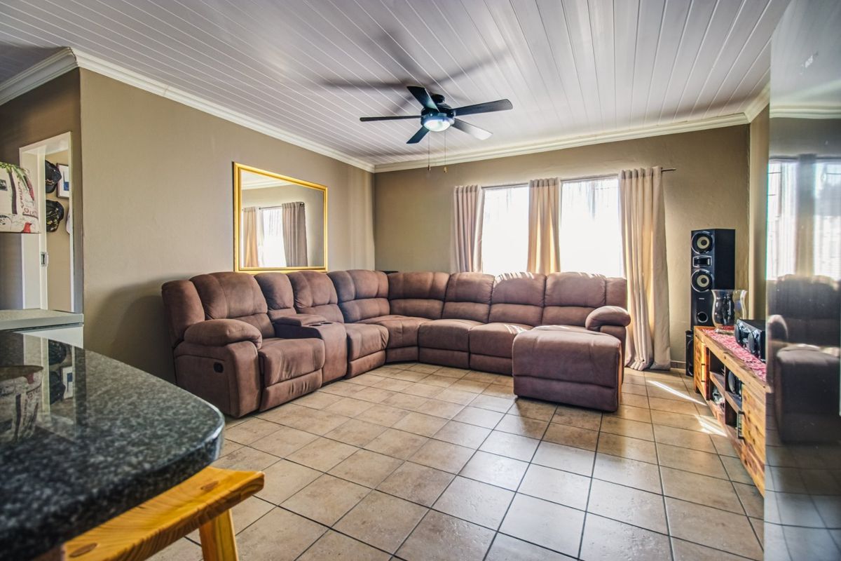 A comfortable living room featuring tiled flooring, a tongue and groove ceiling with a central fan, and neutral wall tones.