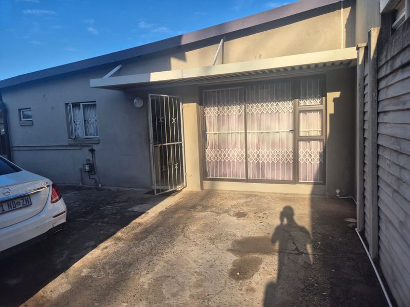 Front exterior view of the property featuring a concrete driveway, security gates, and a sliding door entrance with an overhead awning.