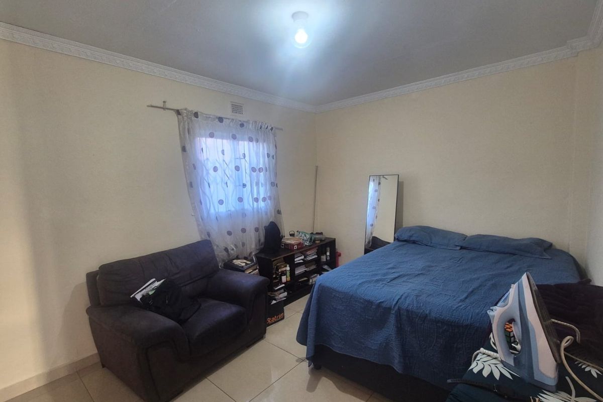 A functional bedroom featuring tiled flooring and decorative ceiling cornicing, providing a neutral base for personalization.