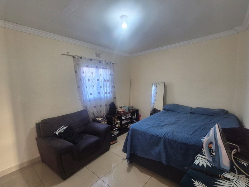 A functional bedroom featuring tiled flooring and decorative ceiling cornicing, providing a neutral base for personalization.