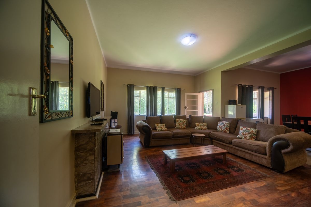 Spacious living room featuring warm parquet flooring, a stone fireplace surround with an integrated gas heater, and natural light through casement windows.