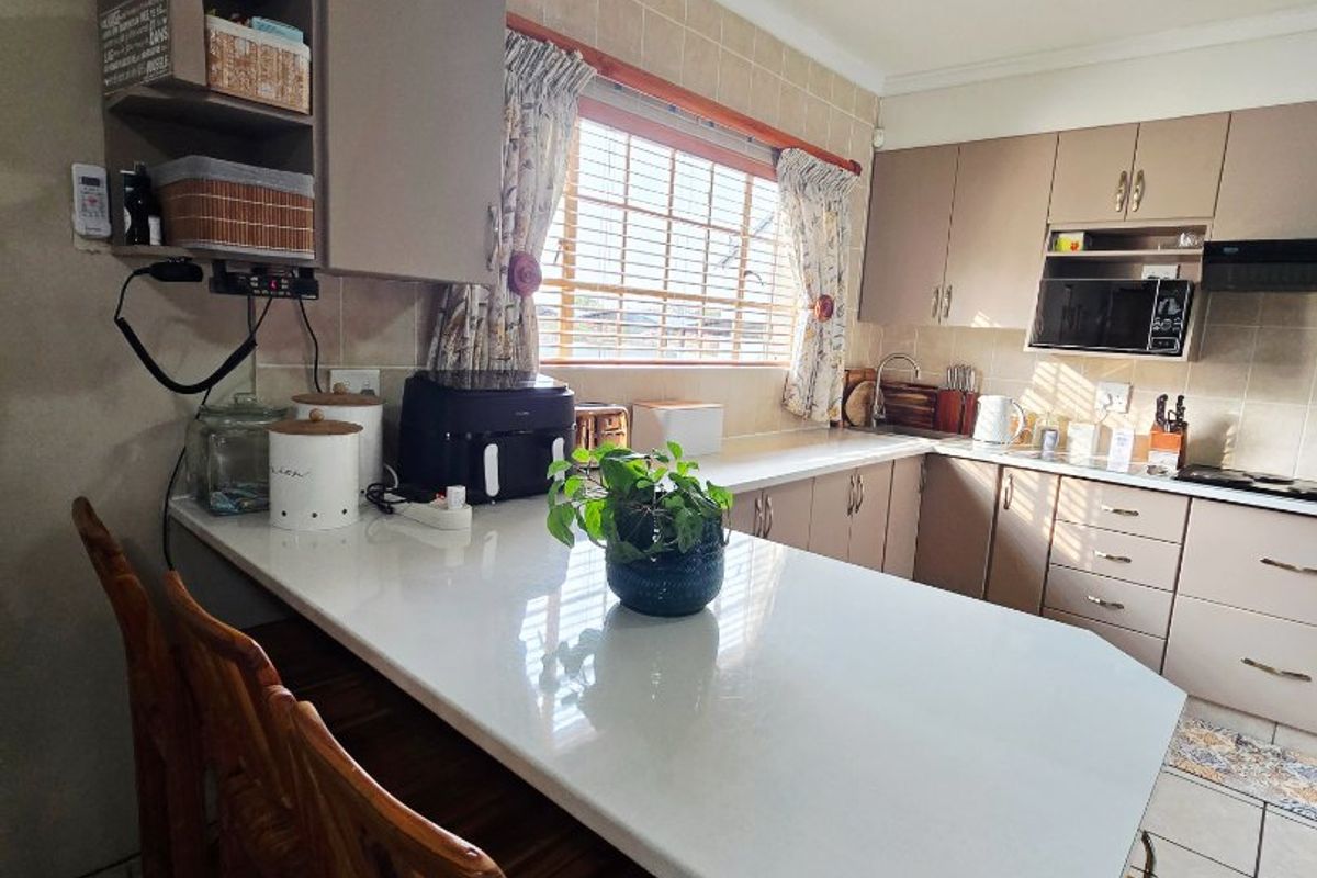 Functional kitchen featuring built-in cabinetry, stone countertops, a breakfast bar, and tiled finishes, offering a practical layout for daily meal preparation.