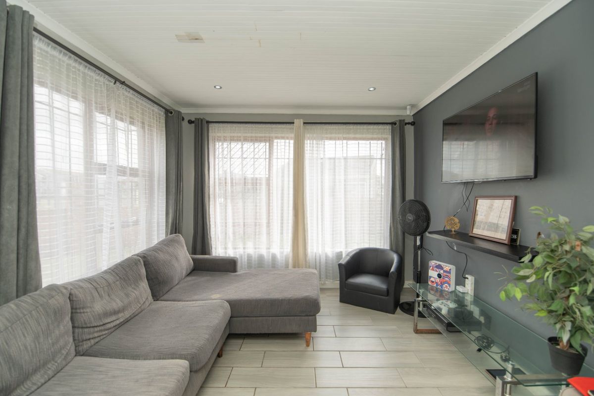 A comfortable living room featuring tiled flooring, recessed downlighting, and a timber tongue and groove ceiling, providing a functional and well-lit space.