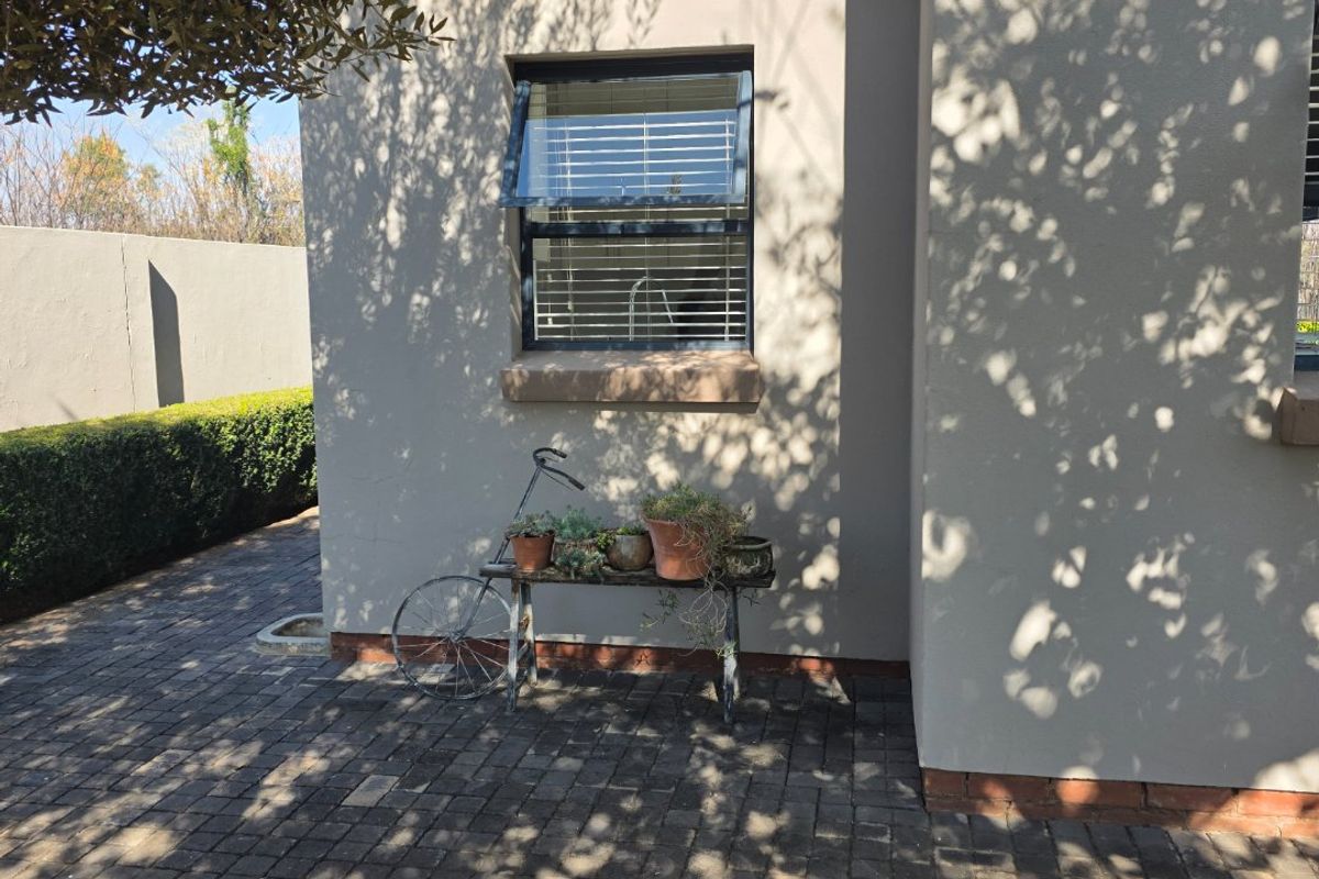 A view of the rear exterior wall featuring a paved patio area and an awning window with a neutral rendered finish.