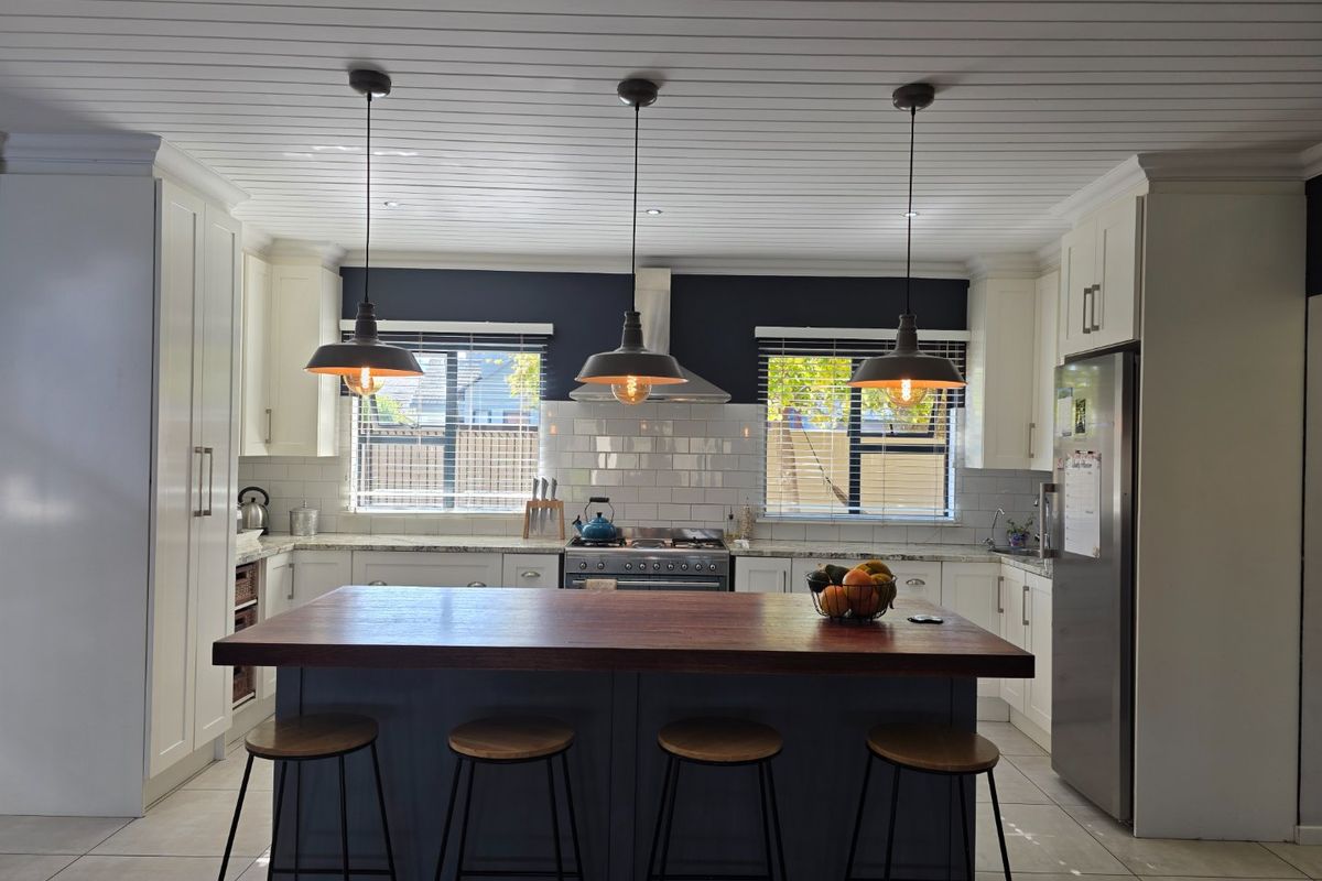 A modern, well-appointed kitchen featuring a central island with a wooden countertop, shaker-style cabinetry, subway tile backsplash, and stainless steel appliances.