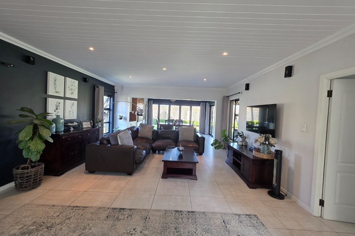 Spacious living room featuring tiled flooring, recessed downlights, and large sliding glass doors providing seamless access to the outdoor area.
