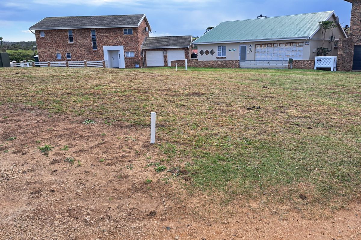 A view of a vacant residential plot of land with surrounding established homes in the background.