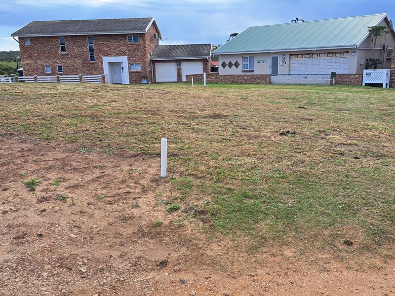 A view of a vacant residential plot of land with surrounding established homes in the background.