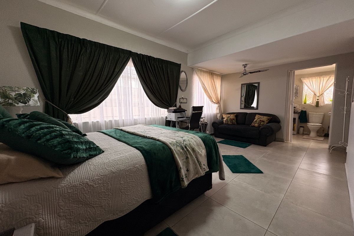 Spacious bedroom featuring tiled flooring, a ceiling fan, and direct access to an en-suite bathroom.