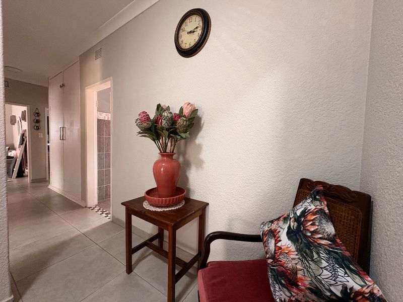 A functional hallway featuring tiled flooring, coved cornicing, and built-in storage cupboards, providing access to adjacent rooms.