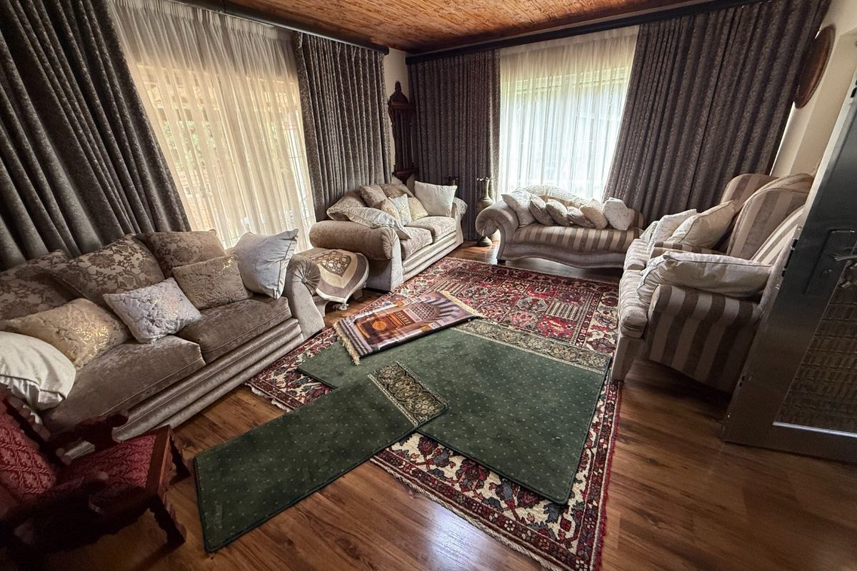 A spacious living room featuring warm timber ceilings, laminate flooring, and large sliding glass doors that provide ample natural light.