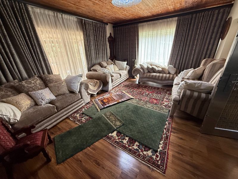 A spacious living room featuring warm timber ceilings, laminate flooring, and large sliding glass doors that provide ample natural light.
