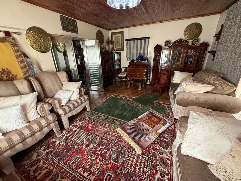 A traditional living room featuring a warm timber ceiling, hardwood flooring, and a decorative metal door, offering a classic and cozy atmosphere.