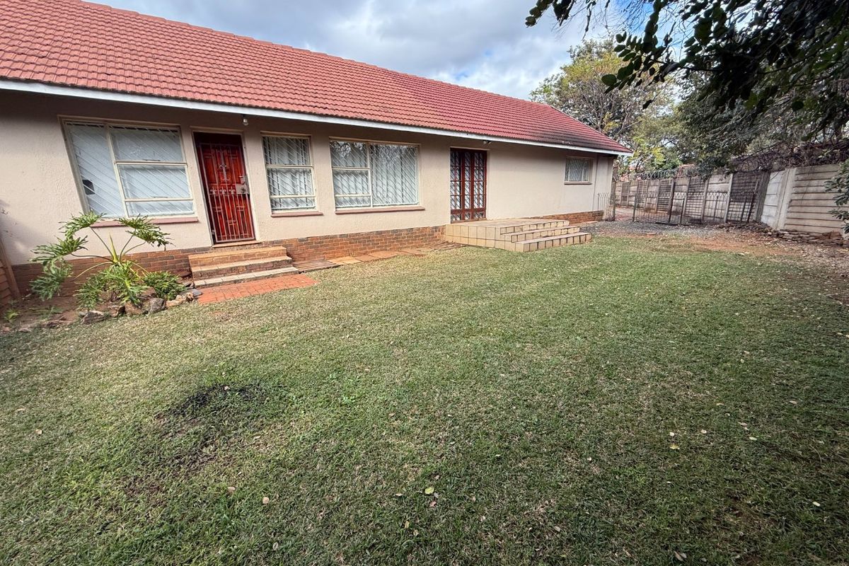 Rear view of the house featuring a tiled roof, brick plinth, and access steps leading to the garden area.
