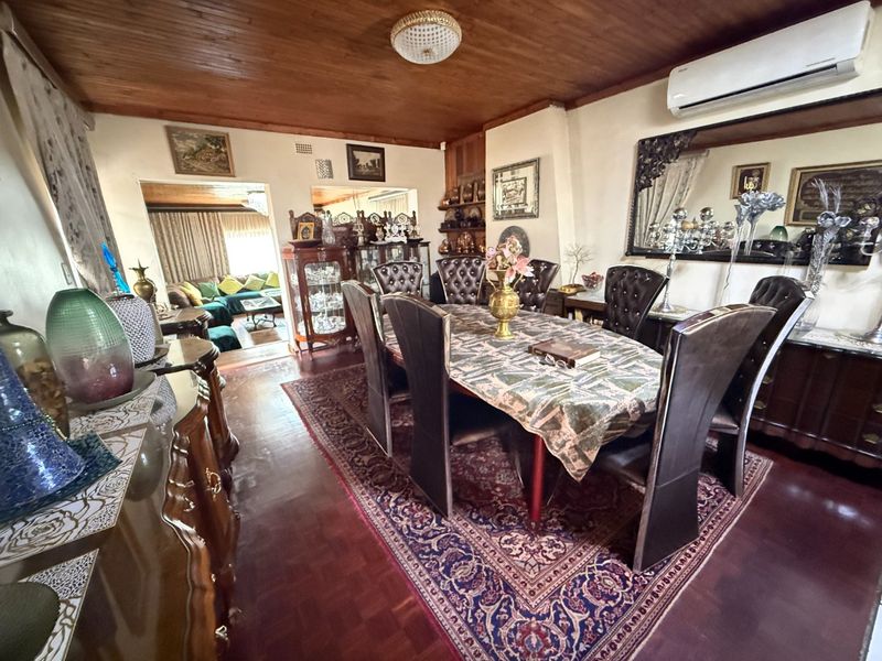 A formal dining room featuring warm timber ceilings, parquet flooring, and a wall-mounted split system air conditioner, with an open flow to the adjacent living area.