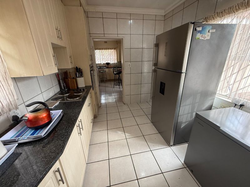 A functional kitchen featuring tiled walls and flooring, granite countertops, and built-in cabinetry with an integrated hob and oven.