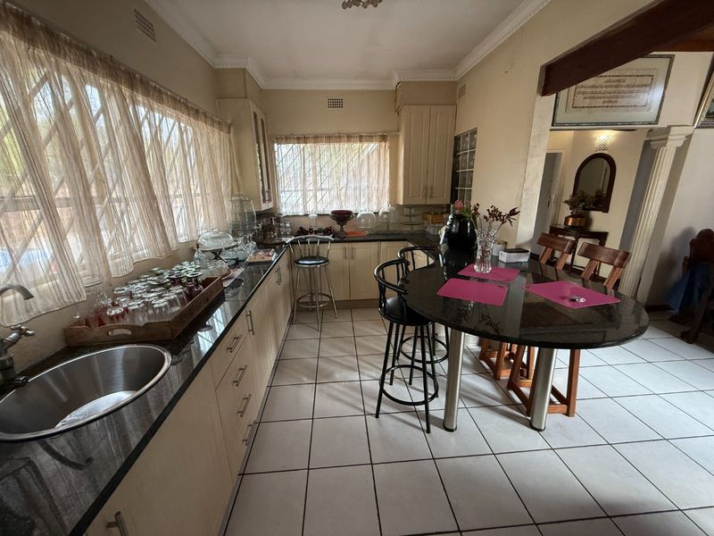 A functional kitchen featuring granite countertops, built-in cabinetry, and ceramic floor tiles, offering a practical layout with an integrated breakfast bar area.