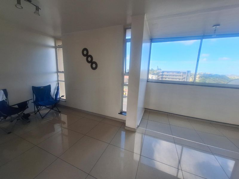 Bright and spacious living area featuring large windows with expansive views, neutral tiled flooring, and modern track lighting.