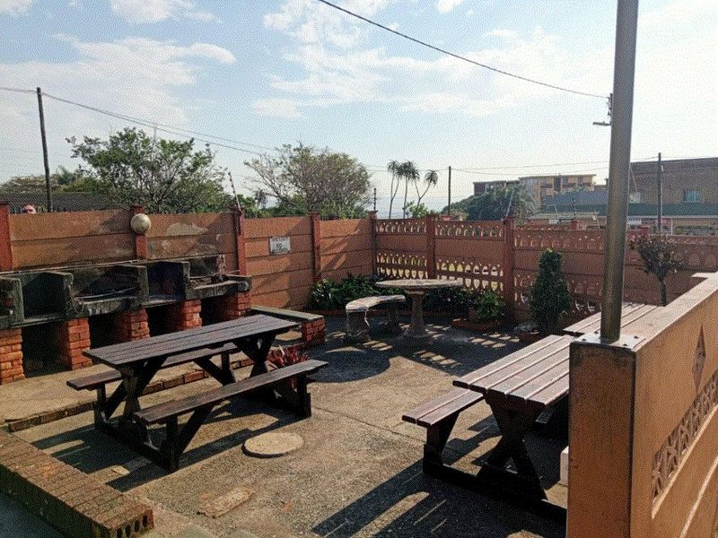 Outdoor patio area featuring a built-in brick braai, concrete paving, and decorative boundary walling, suitable for outdoor entertaining.