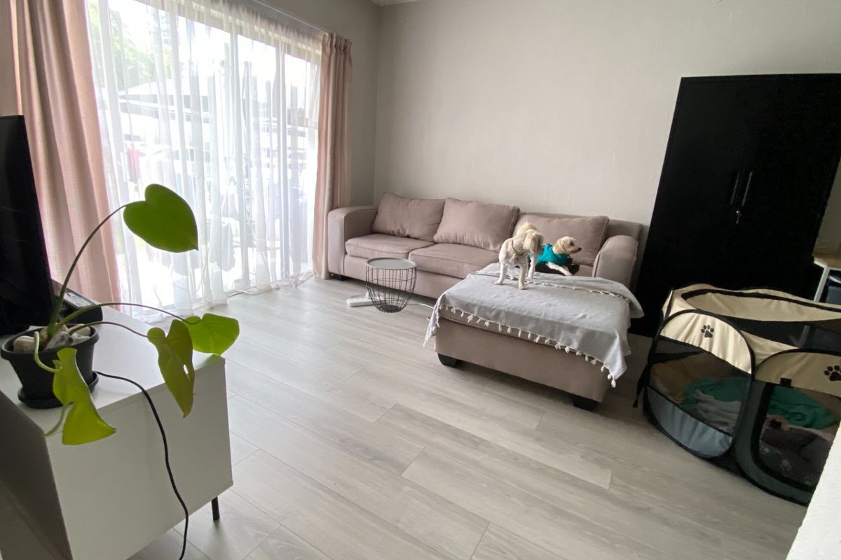 A bright living room featuring light-toned laminate flooring and a large sliding glass door that provides ample natural light.