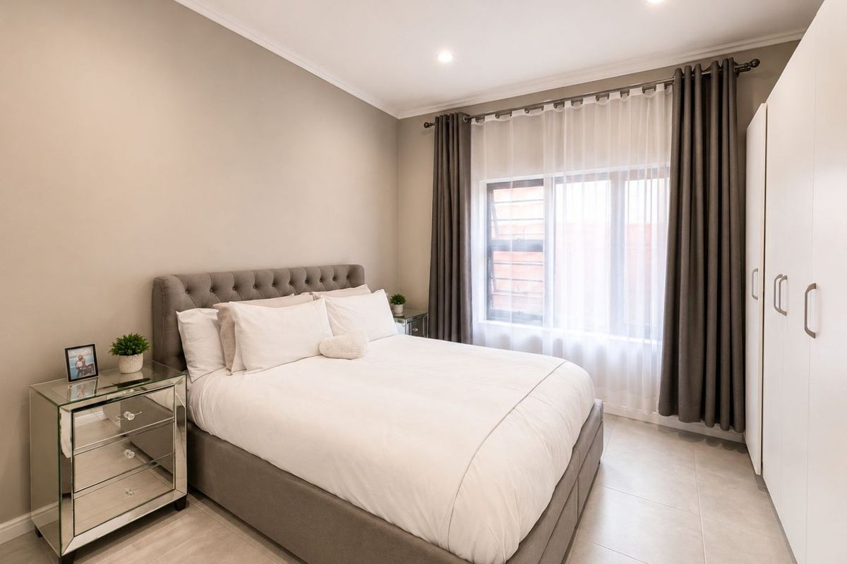 A well-maintained bedroom featuring neutral wall tones, tiled flooring, recessed downlighting, and a built-in wardrobe.