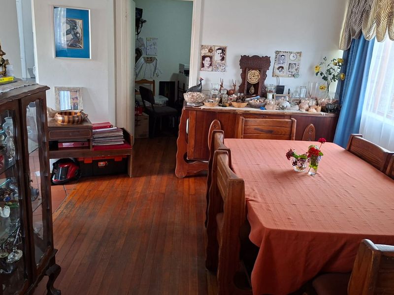 A dining room featuring original hardwood flooring and natural light through large windows, offering a traditional layout with access to adjacent living spaces.