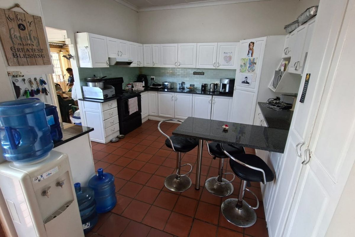 A functional kitchen featuring white cabinetry, dark granite countertops, a subway tile backsplash, and a built-in breakfast bar with tiled flooring.